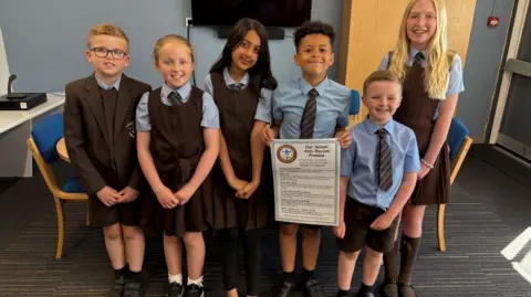 Six pupils at St. Francis of Assisi Primary School with one holding the charter