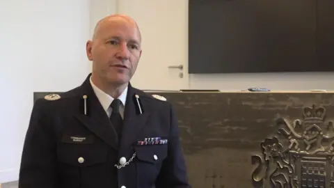 PA Media Commander Dominic Murphy is standing in a courtroom. He is wearing a Met Police uniform and has a balding head
