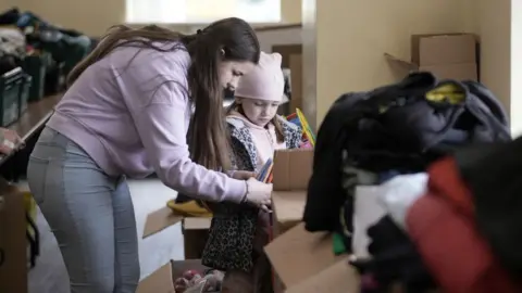 Getty Images Ukrainian refugee children from the City of Buchach volunteer at Ukrainian Cultural Centre 'Dnipro' sorting out humanitarian aid for compatriots in the UK and Ukraine on 29 March 2022 in Manchester, England