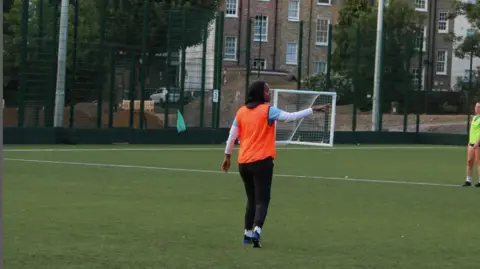 Iqra Ismail Iqra Ismail playing football in a field