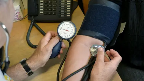 A doctor taking blood pressure reading on a patient's arm.