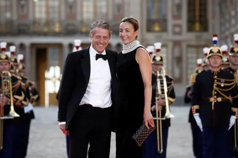 Reuters Hugh Grant and his wife Anna Elisabet Eberstein arrive to attend a state dinner in honour of Britain's King Charles and Queen Camilla at the Chateau de Versailles