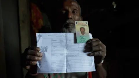 Antariksh Jain Monindra Das holds up his voter ID