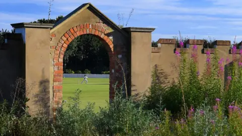 Cricketer playing viewed through an archway