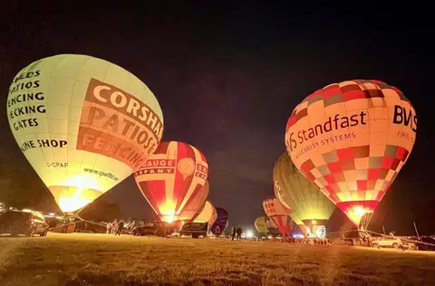 Hot air balloons light up their burners in the dark at the Bristol Balloon Fiesta