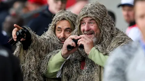 Robin Jones/Southampton FC/Getty Two Saints fans dressed in ghilles and holding binoculars at St Mary's