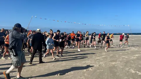Runners starting the race on the beach.
