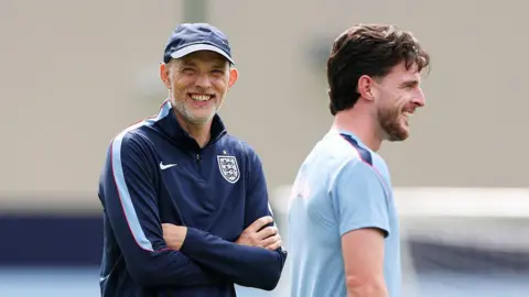 Declan Rice and Thomas Tuchel both smile during an England training session