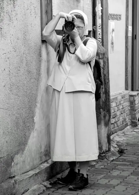 Given a nun hand takes a photo with a camera