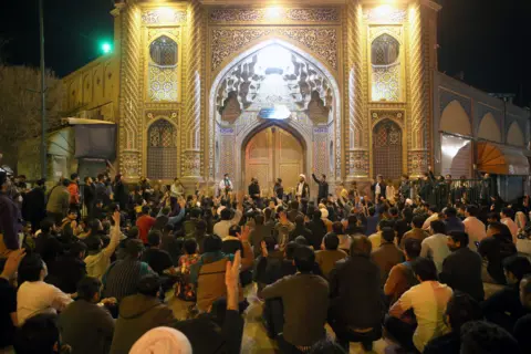 MEHDI MARIZAD People gather outside the closed doors of the Fatima shrine in Iran's holy city of Qom