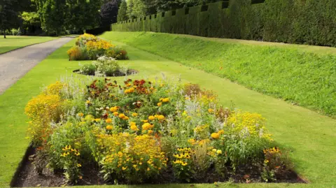 Getty Images The image shows West Dean Victorian Gardens, specifically a small flower patch and a path can be seen going up the left-hand side.