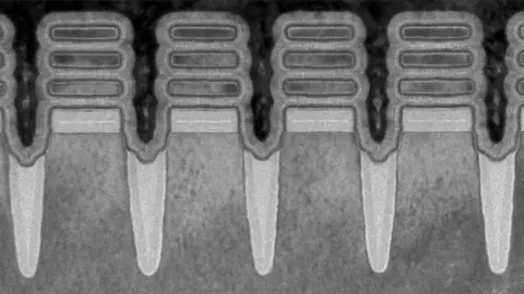 IBM A microspcope image in black and white shows what appear to be four upright pillars with three floating "discs" at their top - a view of the transistors