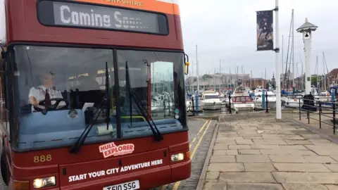 A bus stationary at a stop on the Hull marina