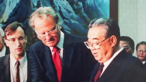 Getty Images Billy Graham (C), the American evangelist, presents his book 'Peace with God' to North Korean President Kim il-Sung (R) 02 April 1992