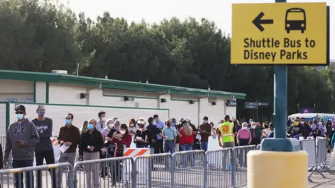 Getty Images People wait in line to receive the Covid-19 vaccine at a mass vaccination site in a parking lot for Disneyland Resort
