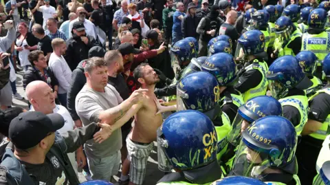 Shutterstock Protesters face a line of riot police in Manchester