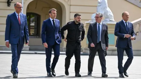 EPA European leaders Merz, Macron, Starmer and Tusk, all wearing suits, walk alongside Zelensky, in dark clothes, across a public square
