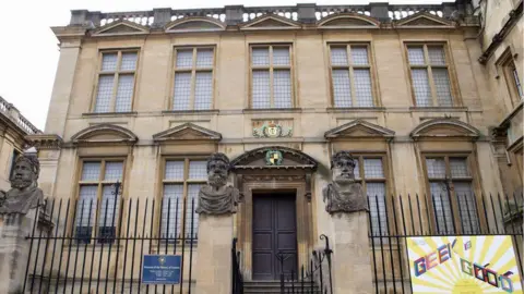 Getty Images An imposing stone building built in a classical style surrounded by black railings and stone pillars topped with stone busts