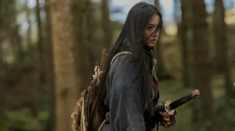 A woman with long dark hair holds a samuai sword