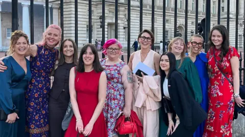 Contributed A group of women standing together and smiling at the camera outside Buckingham Palace.