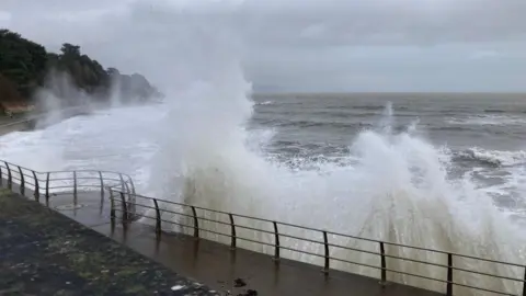 BBC Weather Watcher/Brownowl Seafront promenade with metal railings with large waves bursting over the top.