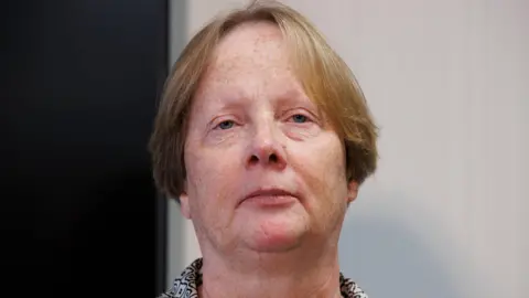 PA Media Elaine McCormill. She is an older woman with shortish, light-coloured hair. She is standing at the podium with a neutral expression on her face.