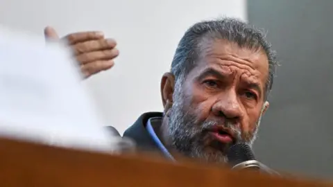EPA Carlos Lupi speaks into a microphone.
