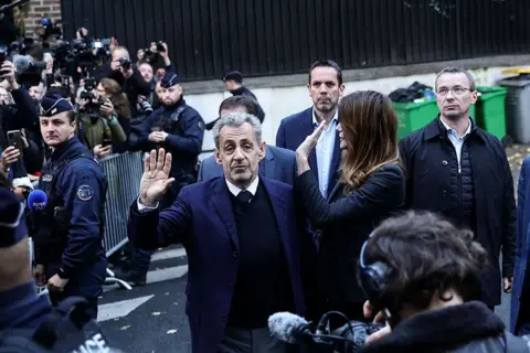 EPA Former French President Nicolas Sarkozy and his wife wave at crowds and photographers on the street before he goes to prison
