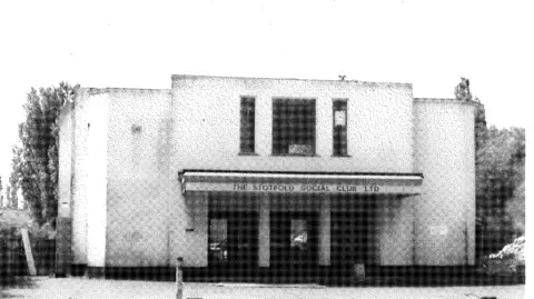 LOCATE INTERNATIONAL A black and white photograph of the Stotfold Social Club as it looked in the 1970's