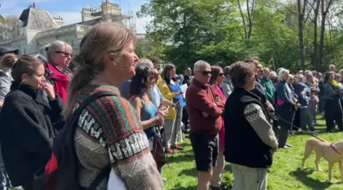 Residents gather at the stump of a tree in protest.