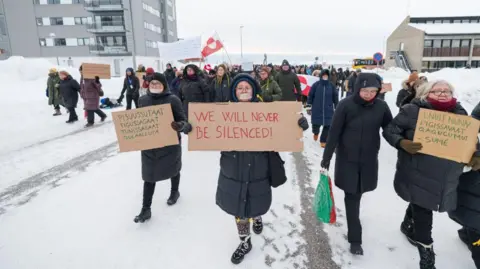 EPA Um grupo de pessoas segurando sinais anti-racismo marcharem juntos na neve como parte de uma demonstração 