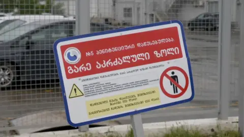 Rayhan Demytrie/BBC A close up picture of a warning sign outside of a Georgian prison. The sign is entirely in Georgian with a warning sign for prohibited access.