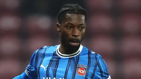 Omar Traore in a blue and black striped FC Heidenheim jersey during a match.
