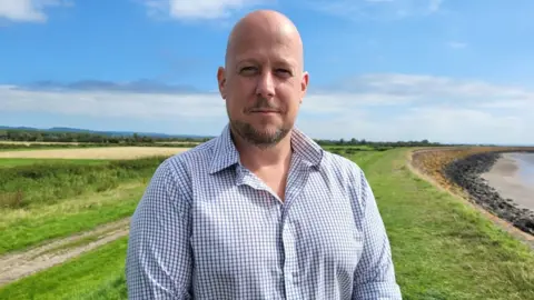 Ross Evans stood on Goldcliff Sea Wall, Gwent Levels