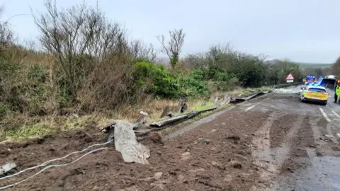 Highways England Soil and debris on a road, with a police car visible on the right
