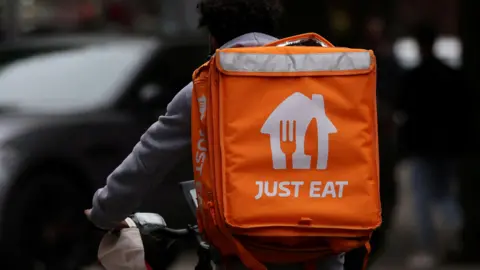Reuters Person riding on a bike with an orange Just Eat food deliver bag on his back 