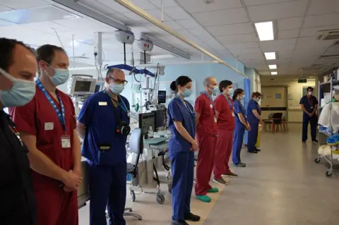 Getty Images Nurses and firefighters stand alongside each other in an ICU ward