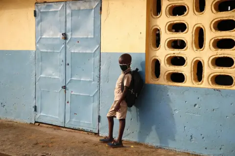 EPA A student wearing a face mask stands outside a classroom.