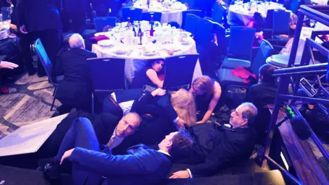 Getty Images WHCA guests seen hiding under the tables and chairs.
