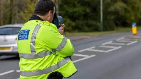 Getty Images Traffic officer with a speed gun checking motorists speed