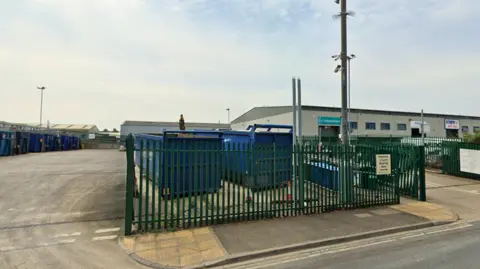 A waste disposal centre with large blue bins on an industrial estate.