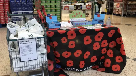 A table is set up at a supermarket entrance but there are no volunteer poppy sellers