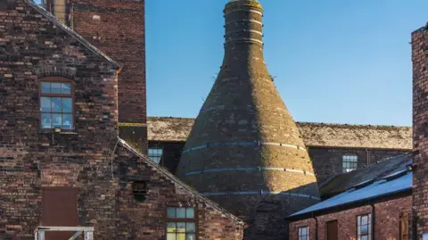 Getty Images Historic buildings of potteries are located on banks of Trent and Mersey canal in Stoke-on-Trent. Factory and kiln rooftops can be seen.