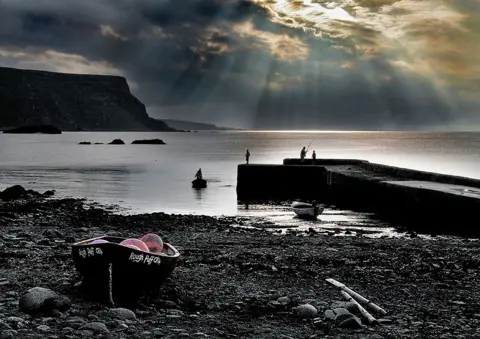 Ian Finlayson A silhouetted beach and harbour wall