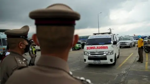 Reuters Thai police look on as an ambulance carrying the body of Australian cricket player Shane Warne leaves at a ferry port in Koh Samui, Thailand
