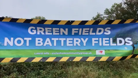 BBC A campaign sign saying "green fields not battery fields"