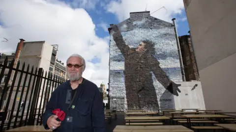 Martin Shields Billy Connolly next to one of his murals