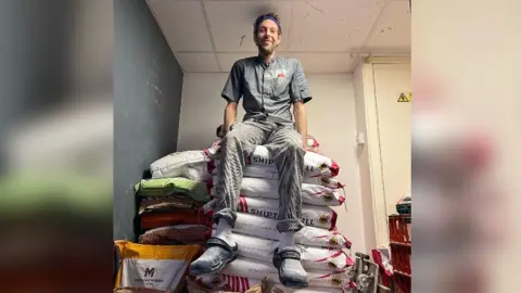 Bakerman Dan Booth sitting on bags of flour