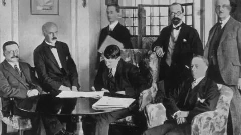 Topical Press Agency/Getty Images Michael Collins signing the Anglo-Irish Treaty on 6 December 1921