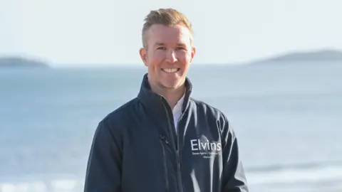 Elvins Estate Agents A man on the coast smiles at the camera 